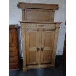 A 20th century blonde oak double door cabinet in an oriental style with metal mounts