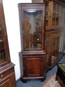 A reproduction mahogany glazed door corner cabinet