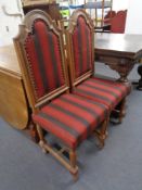 A pair of oak arch-back dining chairs upholstered in a red striped fabric