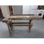 An antique wooden work bench fitted with two vice