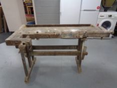 An antique wooden work bench fitted with two vice