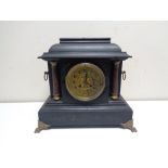 A late nineteenth century French ebonised mantel clock on brass paw feet