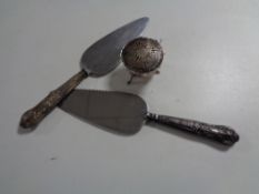 Two silver handled cake slices together with a silver pot with lid on raised legs