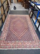 A large fringed Eastern carpet on light pink ground