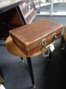 A vintage brown leather suitcase and a lamp table