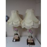A pair of hand painted porcelain table lamps on brass bases with tasselled shades