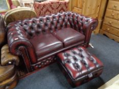 A Burgundy leather two seater Chesterfield settee and matching storage footstool