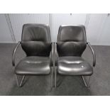 A pair of black vinyl office armchairs on metal legs