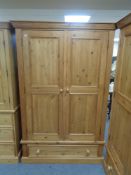 A pine double door wardrobe fitted a drawer