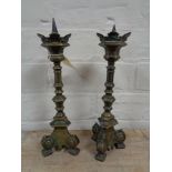 A pair of antique brass candlesticks on tripod feet