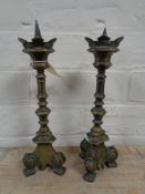 A pair of antique brass candlesticks on tripod feet