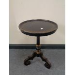 A Victorian ebonised wine table on three way pedestal and gilded decoration