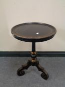 A Victorian ebonised wine table on three way pedestal and gilded decoration