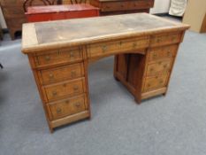 A Victorian Aesthetic period oak writing desk with nine drawers and tooled leather inset panel