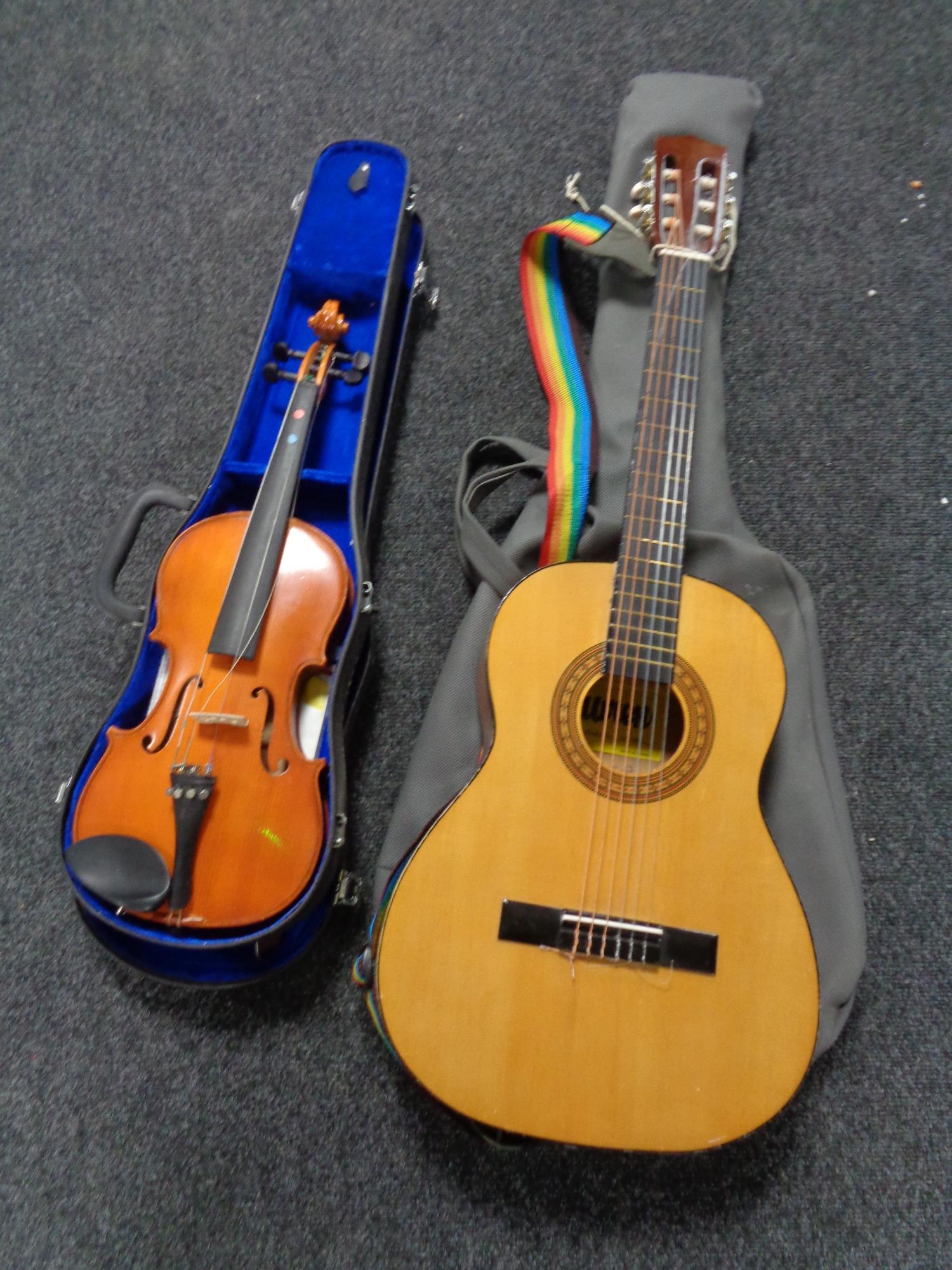 A student violin and bow in case together with an acoustic guitar in carry bag