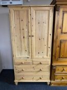 A stripped pine double door wardrobe fitted with four drawers