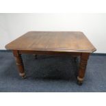 An Edwardian oak wind out table with two leaves