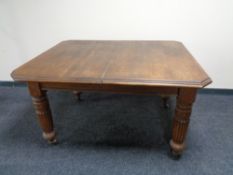 An Edwardian oak wind out table with two leaves