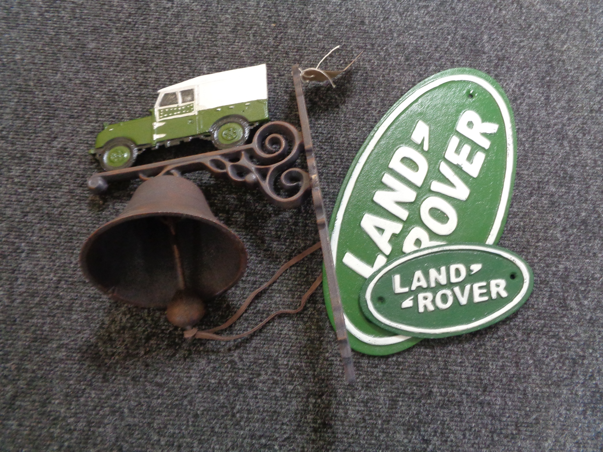 A cast iron Land Rover wall bracket with bell and cast iron Land Rover plaques