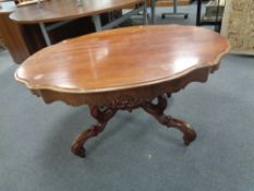 A shaped continental mahogany coffee table on pedestal