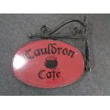A hand painted metal Cauldron Cafe sign on bracket