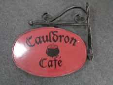 A hand painted metal Cauldron Cafe sign on bracket