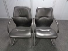 A pair of black vinyl office armchairs on metal legs