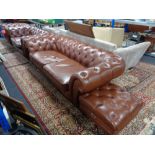 A four piece brown leather Chesterfield lounge suite comprising three seater settee,