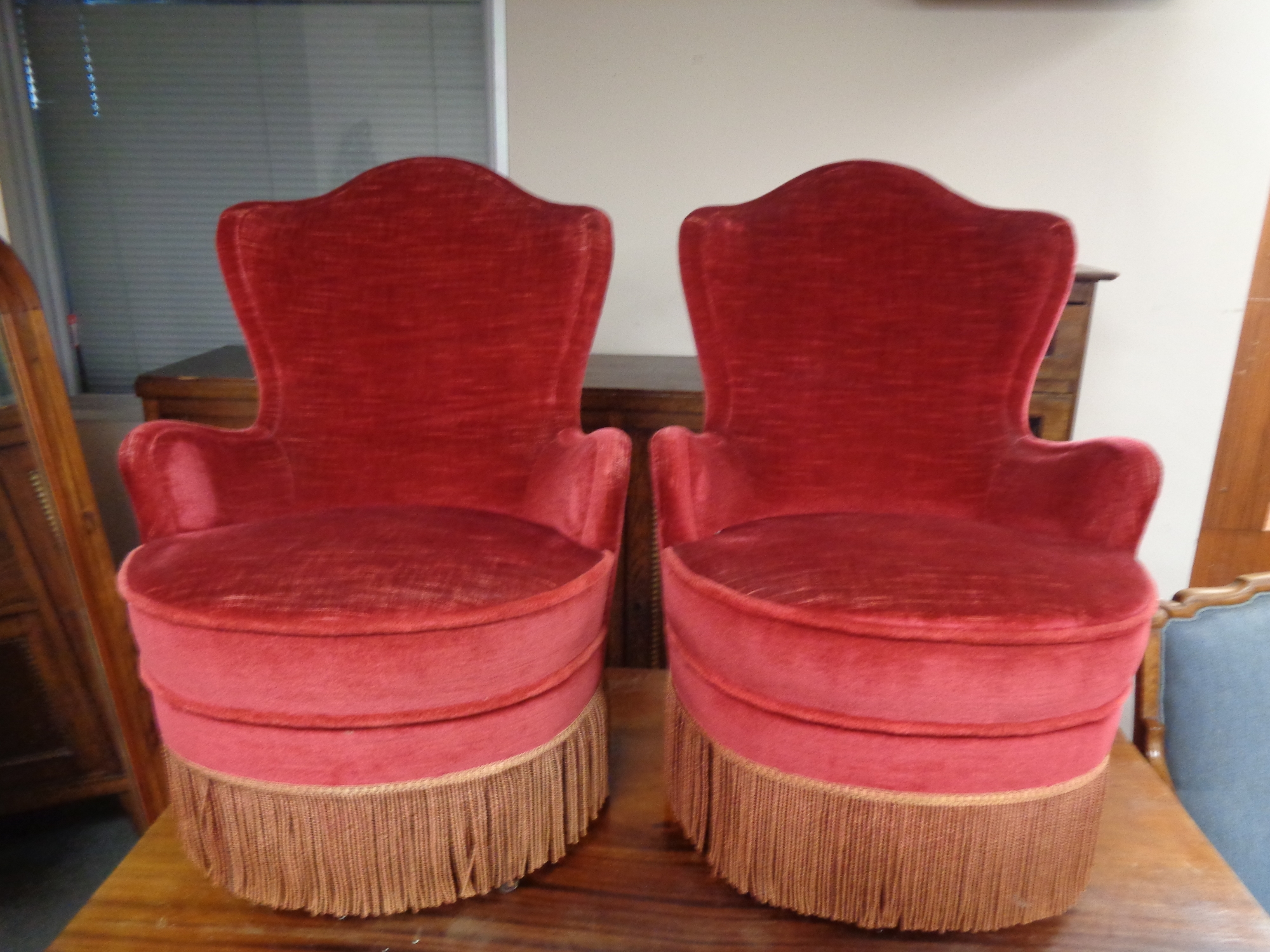 A pair of salon armchairs in red tasselled upholstery