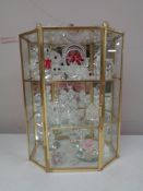 A brass and glass display cabinet containing crystal ornaments, Swarovski and others.