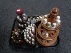 A tray of five wooden thimble display stands and a quantity of china and metal thimbles