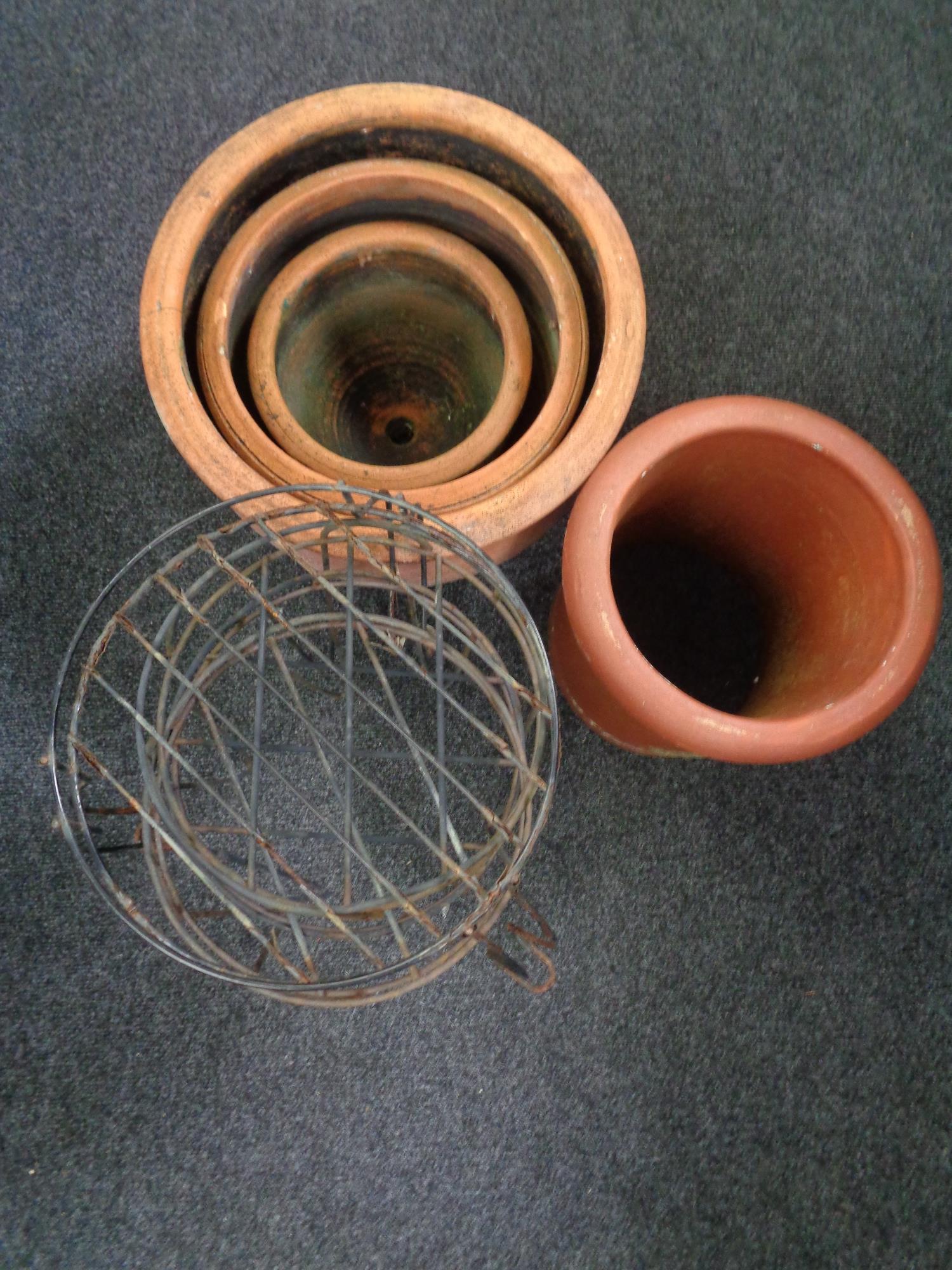 Two terracotta planters and a chimney pot together with three wrought metal stands