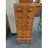 A narrow pine chest on stand fitted with eleven drawers