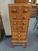 A narrow pine chest on stand fitted with eleven drawers