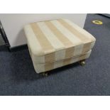 An upholstered footstool in two tone striped fabric