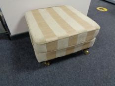 An upholstered footstool in two tone striped fabric
