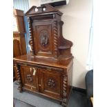 A nineteenth century heavily carved oak sideboard with barley twist supports fitted with cupboards