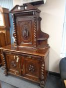 A nineteenth century heavily carved oak sideboard with barley twist supports fitted with cupboards