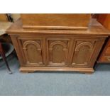 An oak low sideboard fitted with three doors