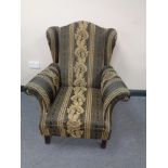 A wing backed armchair in classical upholstery