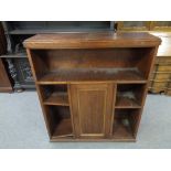 An early twentieth century oak open bookcase fitted a central cupboard