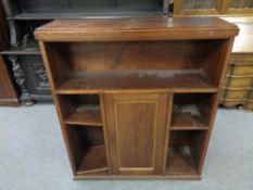 An early twentieth century oak open bookcase fitted a central cupboard