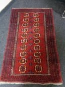 An Afghan design rug on red ground