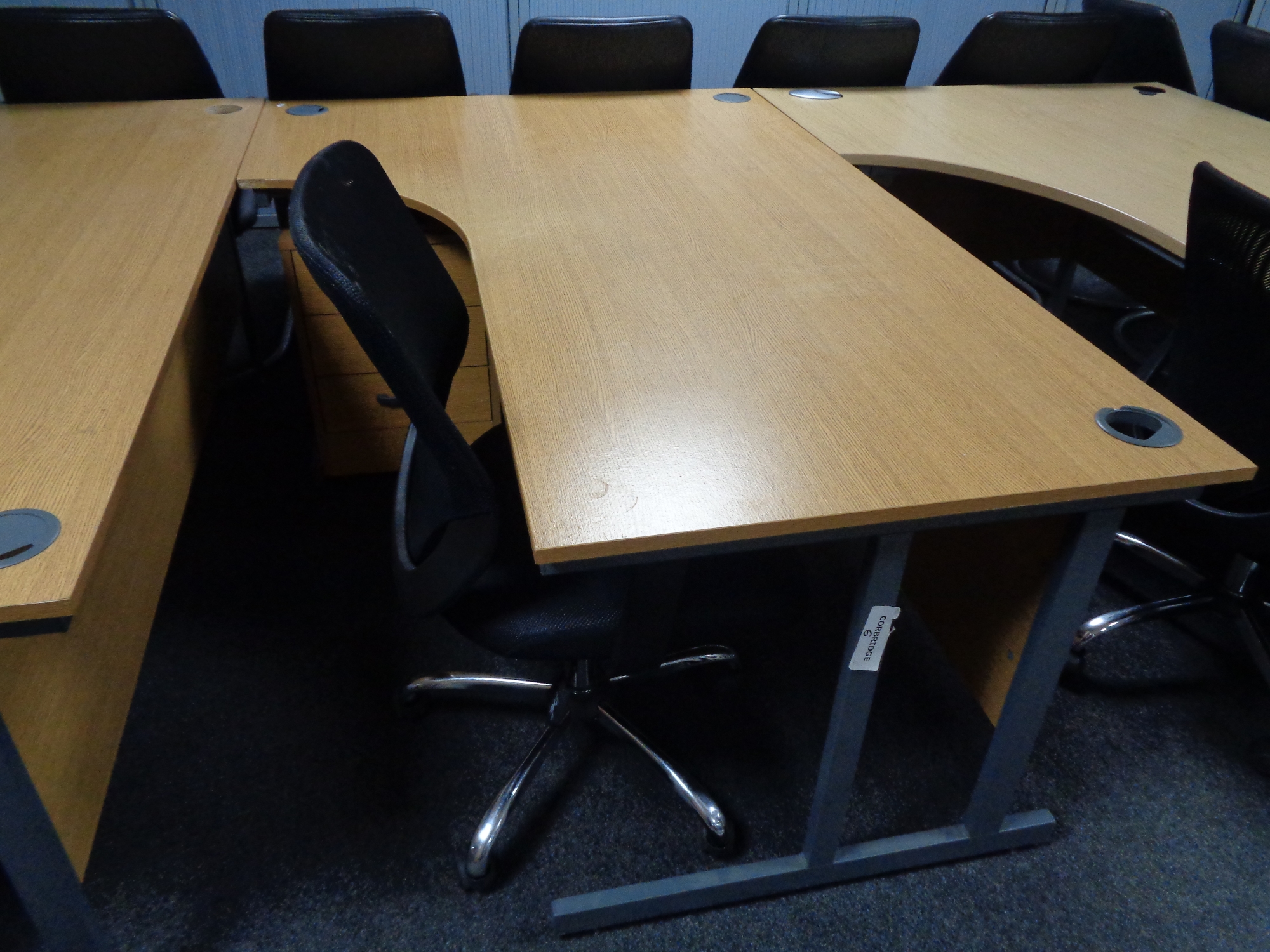 A corner office desk with three drawer pedestal and swivel adjustable armchair