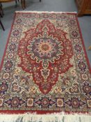 A machine made Persian design carpet on red ground 242 cm x 161 cm