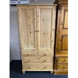 A stripped pine double door wardrobe fitted with four drawers