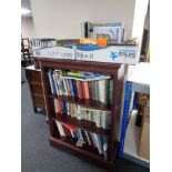 A set of mahogany effect open bookshelves containing books and two further boxes of books