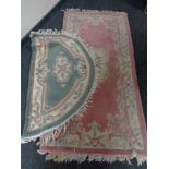 A pink fringed Chinese floral rug and a green fringed d-shaped rug