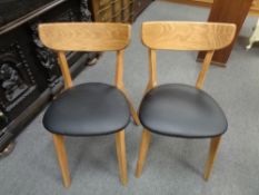 A set of four Danish oak dining chairs with black vinyl seats