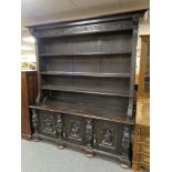 A heavily carved oak bookcase fitted with cupboards beneath